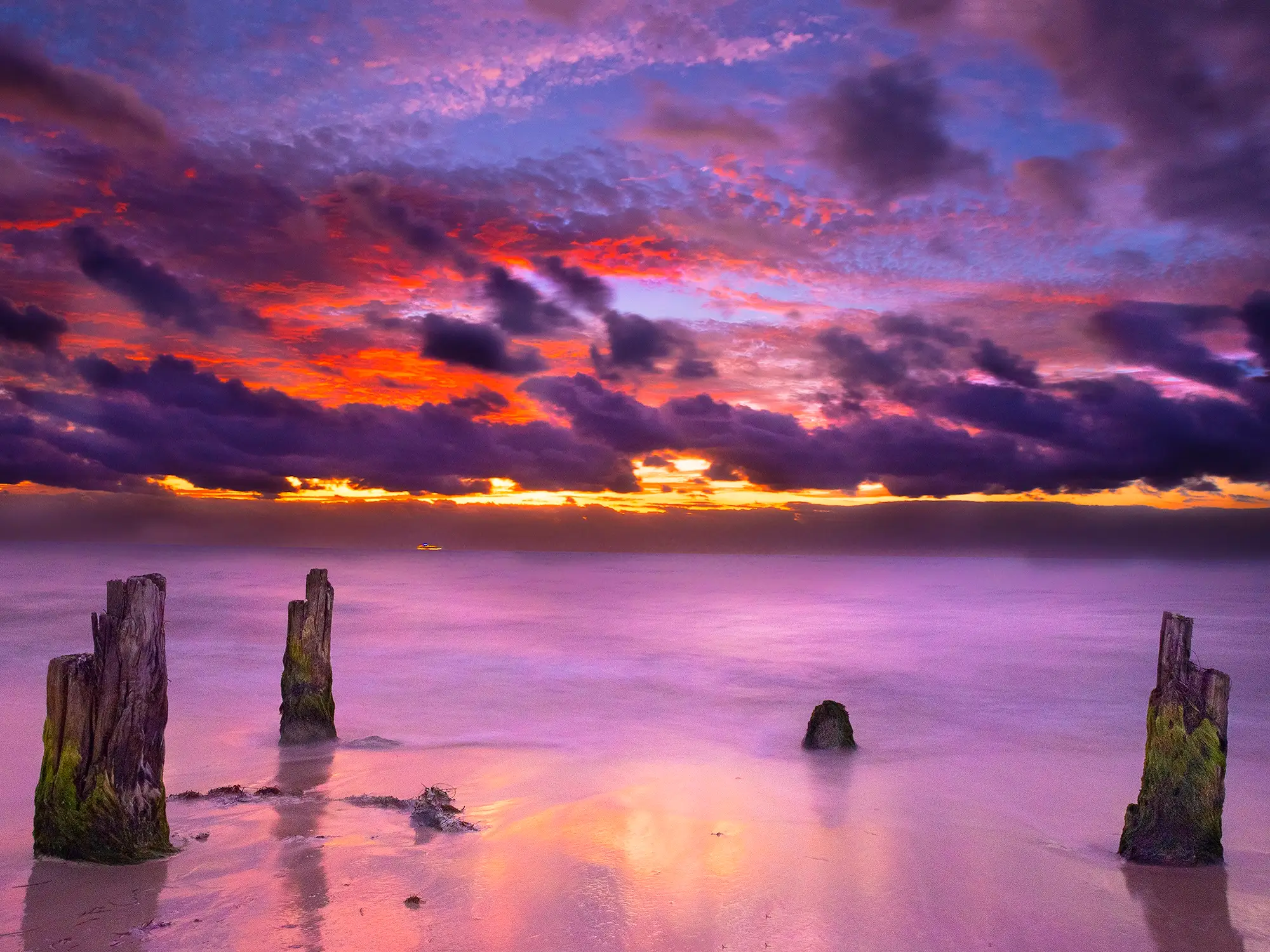 Ember sunset over still water and weathered pilings at Puerto Morelos. Photograph by Reed Rahn